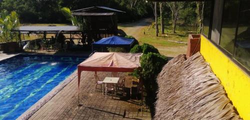 a table next to a swimming pool next to a building at Grand Selva Lodge & Tours in Tena