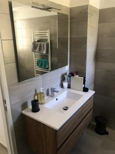 une salle de bain avec un lavabo et un miroir dans l'établissement Appartement moderne à Bastia de 57 m² avec vue mer exclusive, à Bastia