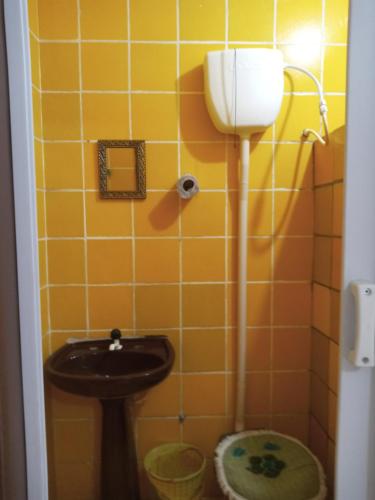 a bathroom with a sink and a yellow tiled wall at Pousada Jardim do Éden in Parnamirim