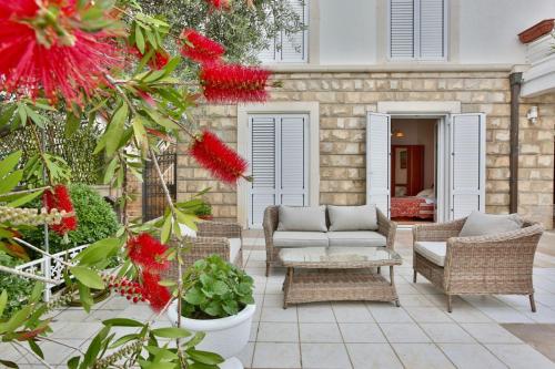 a patio with a couch and chairs and red flowers at Royal Holiday Apartments Sveti Stefan in Sveti Stefan