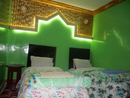 a green room with two beds and a green wall at Maison D'hôtes Chez Bassou Agoudal in Agoudal