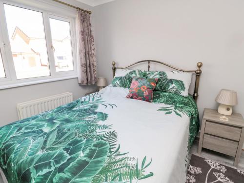 een slaapkamer met een bed met een bedsprei met groene bladeren bij 20 Southmead in Morpeth