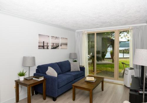 a living room with a blue couch and a window at Oceanfront Suites at Cowichan Bay in Cowichan Bay