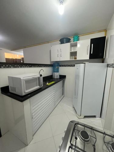 una pequeña cocina con microondas y nevera. en Hospedagem Central III, en Arraial do Cabo