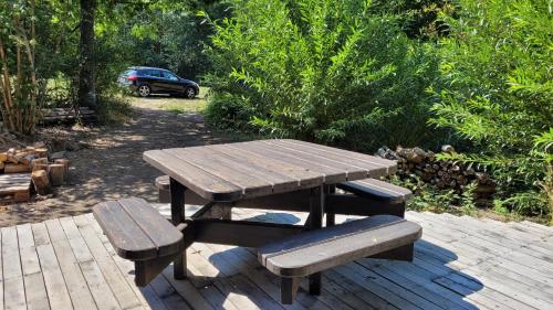 a wooden picnic table and benches on a patio at La Grenouillette in Mirwart