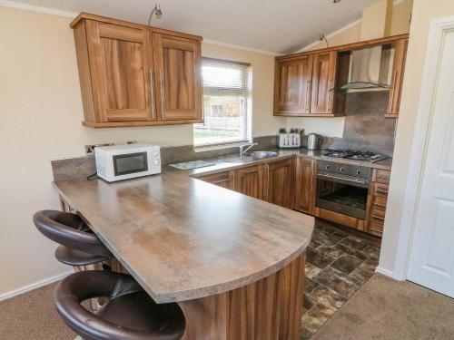 a kitchen with wooden cabinets and a counter with a microwave at Gressingham 22 in Carnforth