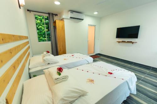 two beds in a room with a flat screen tv at Ramzu Villa Thoddoo in Thoddoo