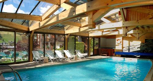 einen Innenpool mit Stühlen und einer Holzdecke in der Unterkunft Hôtel Les Côtes, Résidence Loisirs et Chalets in Morzine