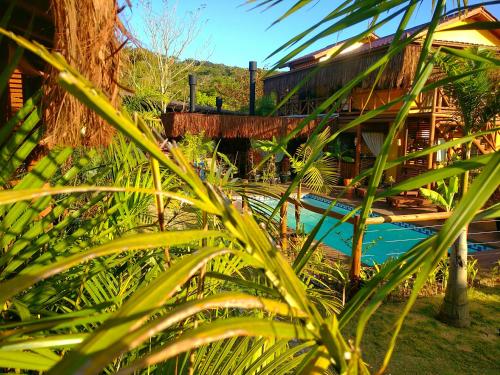 a view of a house from behind some plants at Pousada Rosa Astral ॐ in Praia do Rosa