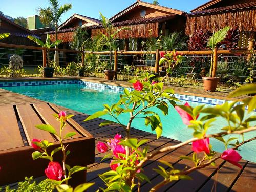 a swimming pool in front of a house with pink flowers at ॐ Rosa Astral ॐ in Praia do Rosa