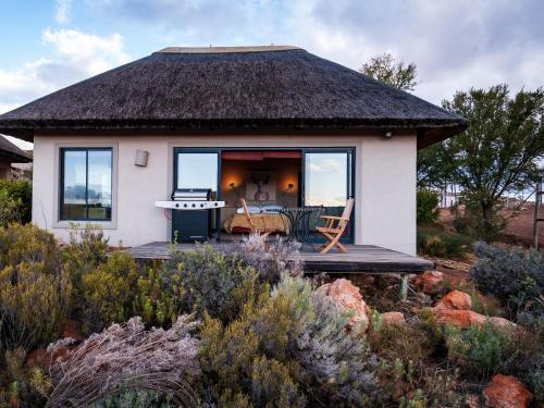 a small house with a thatched roof in a garden at Rooilande Guest Farm in Laingsburg