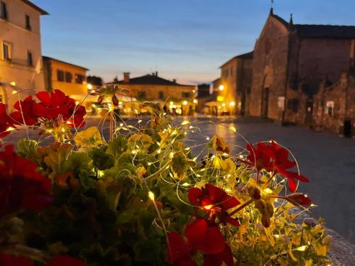 a flower pot with red flowers and lights on a street at Monteriggioni Castello in Monteriggioni