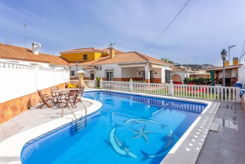 a swimming pool with two chairs and a table at Villa espectacular in Rincón de la Victoria
