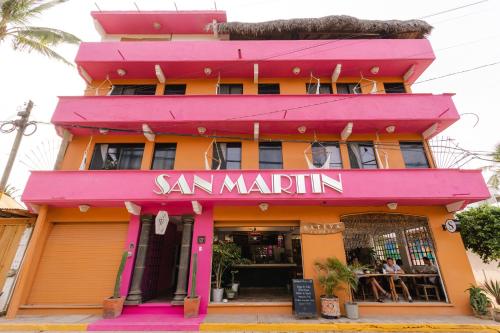 a pink and orange building with a restaurant at Hotel San Martin La Punta in Puerto Escondido