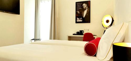 une chambre d'hôtel avec un lit et un fauteuil rouge dans l'établissement Lisbon City Hollywood Hotel by City Hotels, à Lisbonne