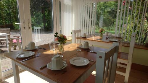 a dining room with a wooden table with plates andoverty at Rossclare Lodge in Enniskillen