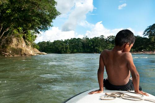 a young man sitting on a surfboard in the water at Grand Selva Lodge & Tours in Tena