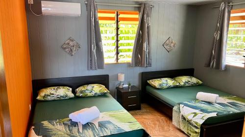 Cette chambre comprend 2 lits et 2 fenêtres. dans l'établissement Hiti Tikehau, the ocean side bungalow, à Tikehau