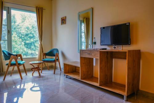 a living room with a television on a wooden entertainment center at Hotel Sarai Bharatgarh in Chandīgarh