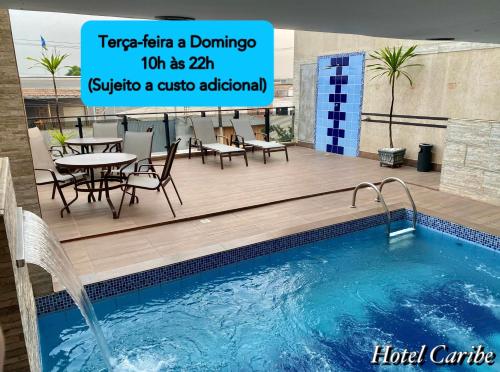 a swimming pool with a table and chairs next to a building at Hotel Caribe in Porto Velho