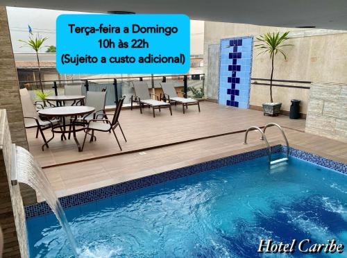 einen Pool mit einem Tisch und Stühlen neben einem Gebäude in der Unterkunft Hotel Caribe in Porto Velho