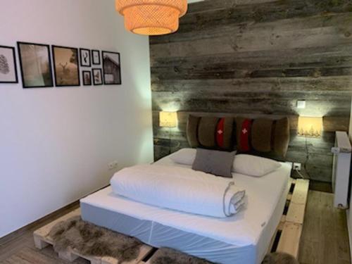 ein Schlafzimmer mit einem weißen Bett und einer Holzwand in der Unterkunft Charmant appart 4 pers avec balcon, parking & WiFi - FR-1-198-211 in Châtel