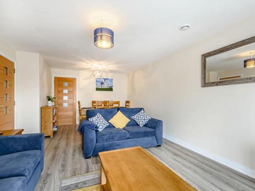 a living room with a blue couch and a table at Oystercatcher in Drummore