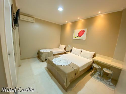 a hotel room with two beds and a table at Hotel Caribe in Porto Velho