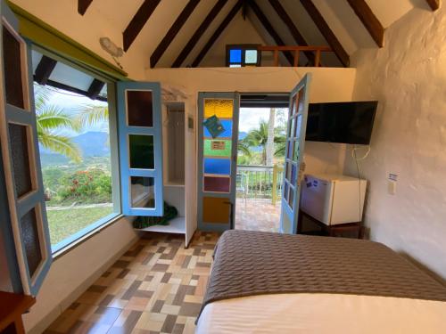 a bedroom with a bed and a tv and windows at Cabañas y Flores in Jericó