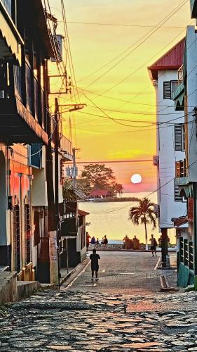 a person walking down a street with the sunset in the background at AMINA Inn in Flores