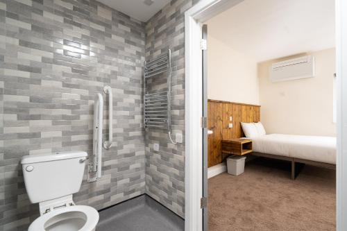 een badkamer met een toilet en een bed in een kamer bij Hotel DC, Stratford in Londen