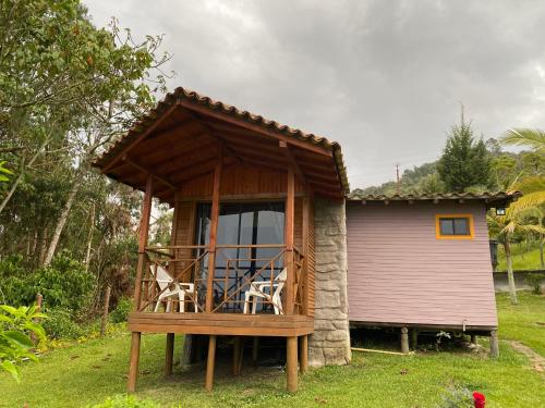 a small house with a balcony with chairs in it at Cabañas y Flores in Jericó