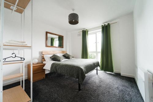 a bedroom with a bed with green curtains at Lovely 2 bedroom flat next to Victoria Park in London