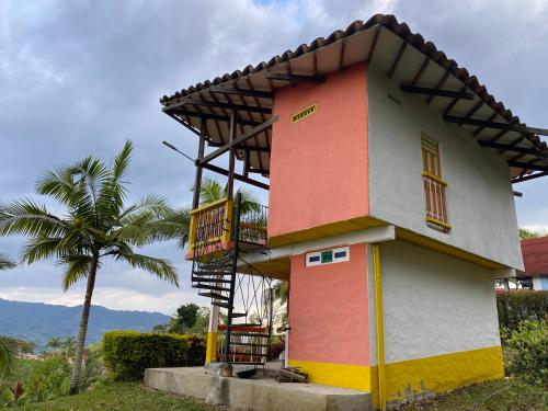 a small house with a balcony and a palm tree at Cabañas y Flores in Jericó
