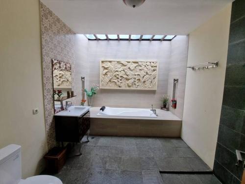 uma casa de banho com uma banheira e um lavatório em Griya Bayan Kraguman Vila 2 Kamar Tidur 
