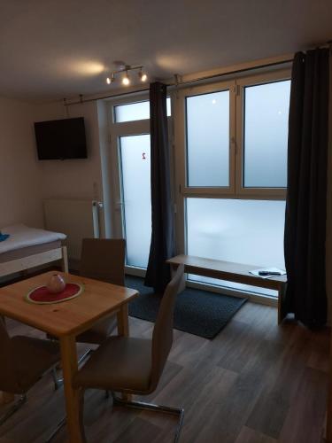 ein Wohnzimmer mit einem Tisch, Stühlen und einem Fenster in der Unterkunft City Pension Senftenberg / Apartment Nr.2 in Senftenberg