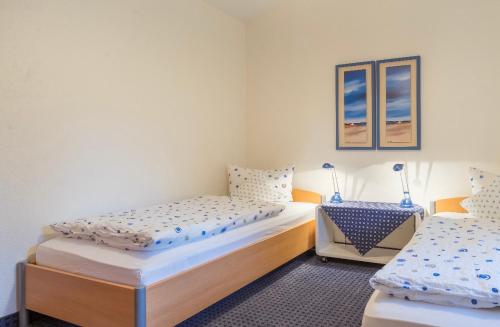 2 łóżka pojedyncze w pokoju ze stołem w obiekcie Haus Kleemann w mieście Norderney