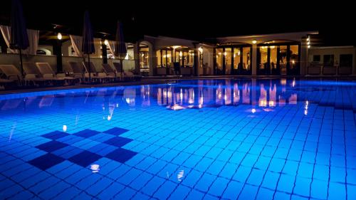 una grande piscina notturna con illuminazione blu di Hotel Villa Letan a Fažana