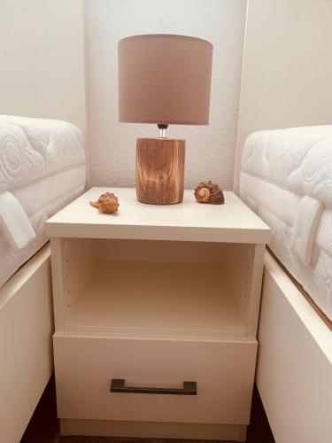a nightstand with a lamp on it next to two beds at Ostseebrise-Fehmarn in Fehmarn