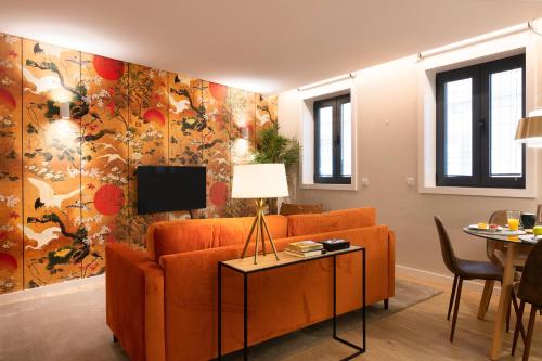 a living room with an orange couch and a tv at Byobu Apartment, by Bolhão Residences in Porto