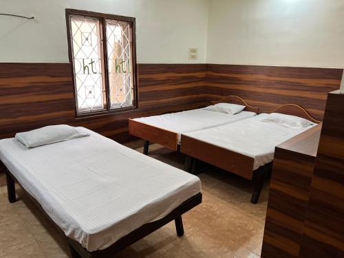 two twin beds in a room with a window at HOTEL THILAK in Tuticorin