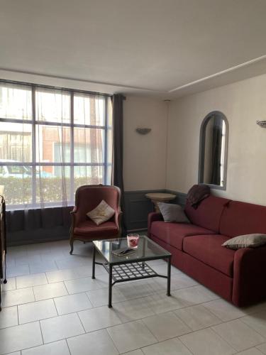 a living room with a red couch and a coffee table at L’orthographe in Villers-Cotterêts