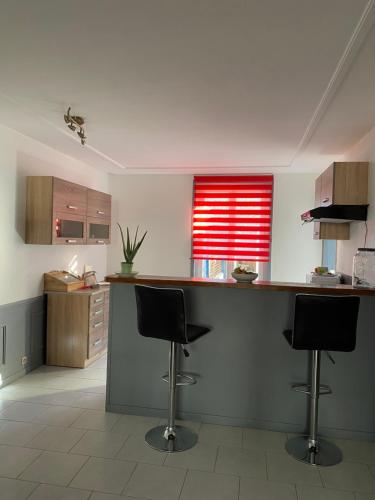 a kitchen with a counter and two bar stools at L’orthographe in Villers-Cotterêts