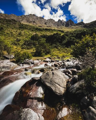 a stream in a mountain valley with rocks at El Albergue Ollantaytambo in Ollantaytambo