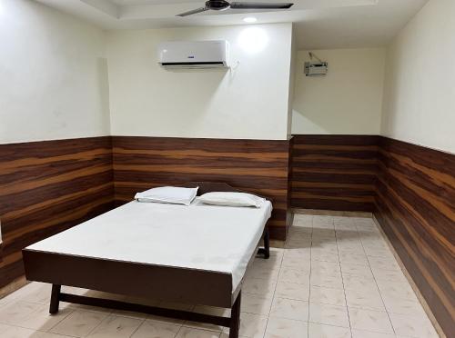 a room with a bed in a room with wooden walls at HOTEL THILAK in Tuticorin