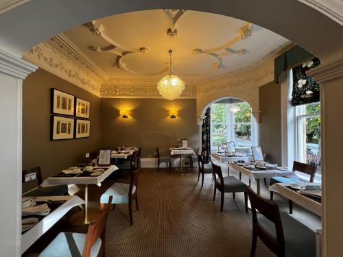 a dining room with tables and chairs and a chandelier at Ascot House in Harrogate