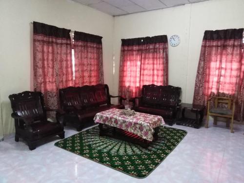 a living room with chairs and a table and red curtains at Homestay Haji Hamid in Pantai Cenang