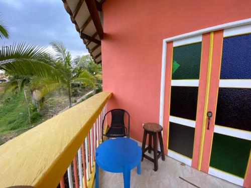 a balcony with a colorful house with a blue stool at Cabañas y Flores in Jericó