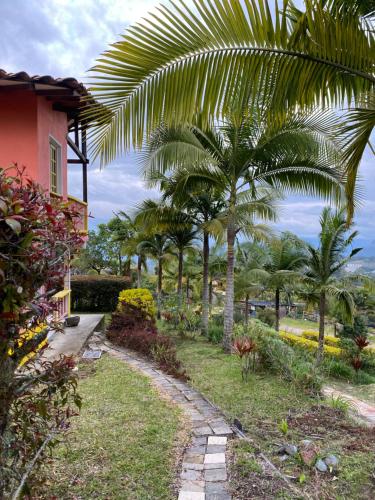 a garden with palm trees and a house at Cabañas y Flores in Jericó