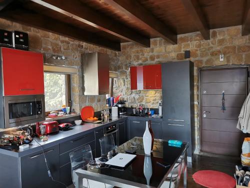 a kitchen with red cabinets and a table in it at Mountain stone villa, sea & mountain view at 1150m in Synikia Mesi Trikalon